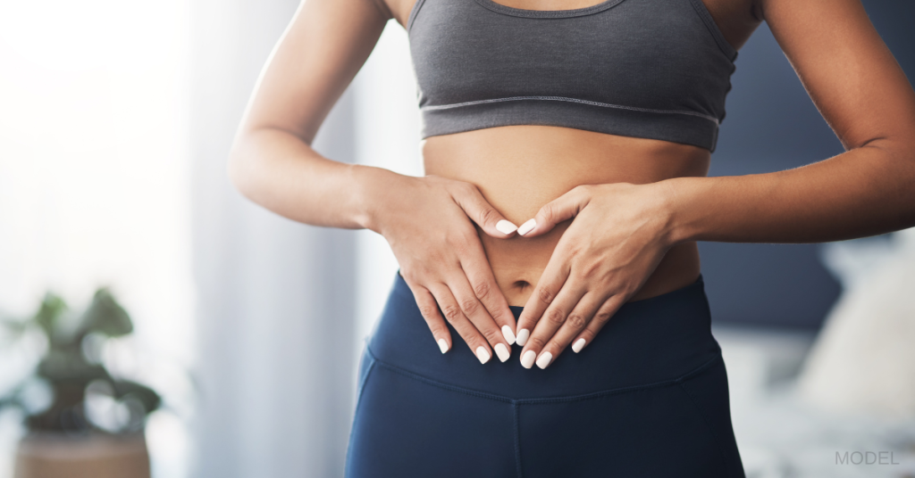 Women with her hand on her stomach after a successful Tummy Tuck procedure (model)