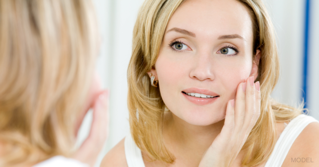 Women touching her face in the mirror (model)