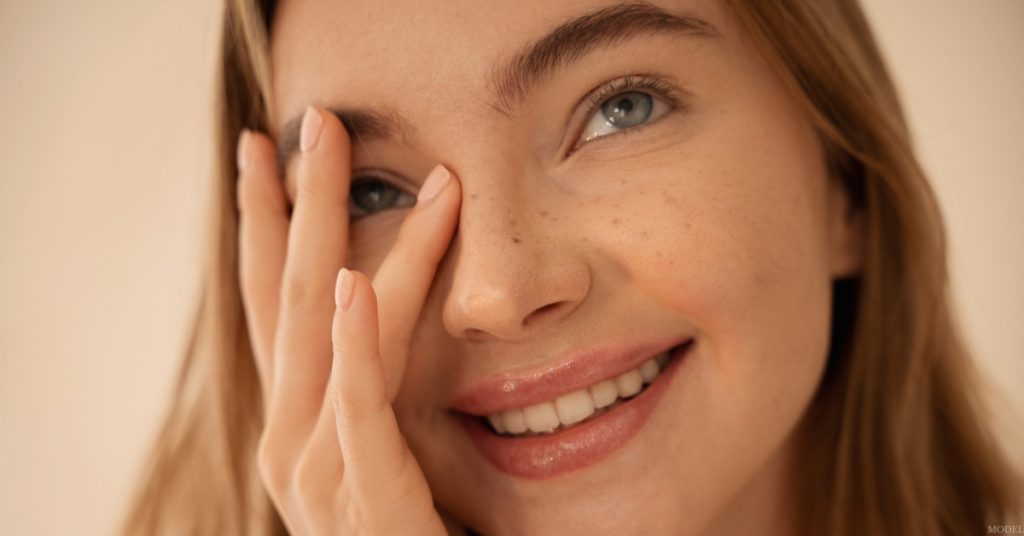 Close-up of a woman touching her nose, representing rhinoplasty results (model)
