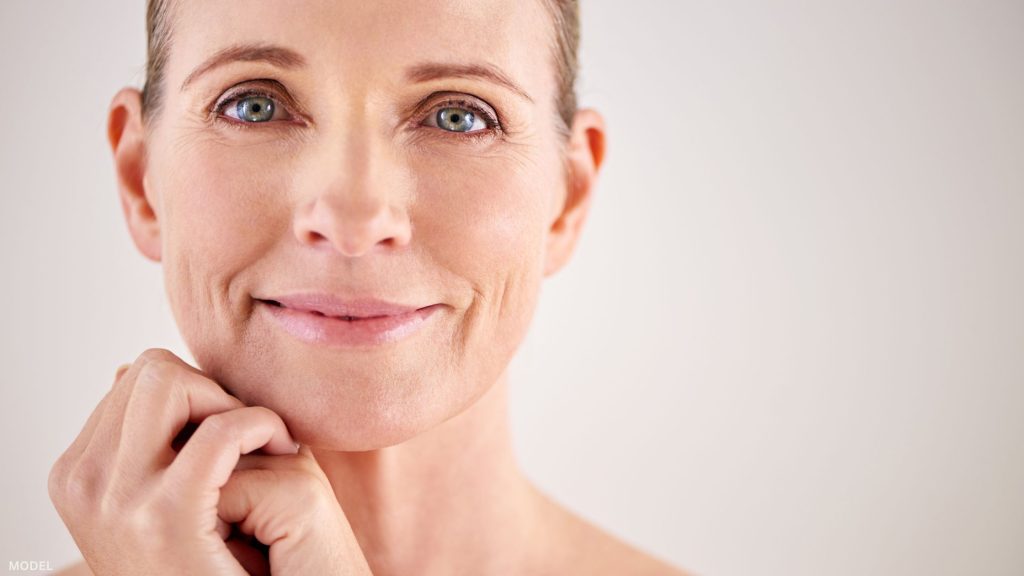 Mature woman looking forward with cupped hands under jaw (model)