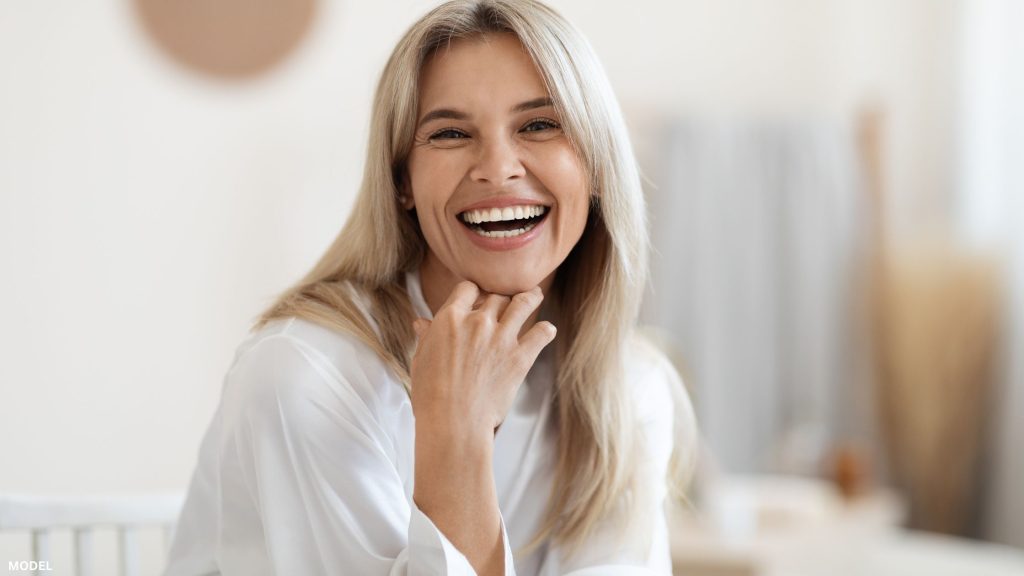 Mature woman laughing with hand under chin (model)