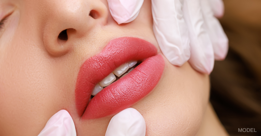 White woman's face (model) with just lips and part of nose showing and a set of hands wearing latex gloves touching each side of her face.